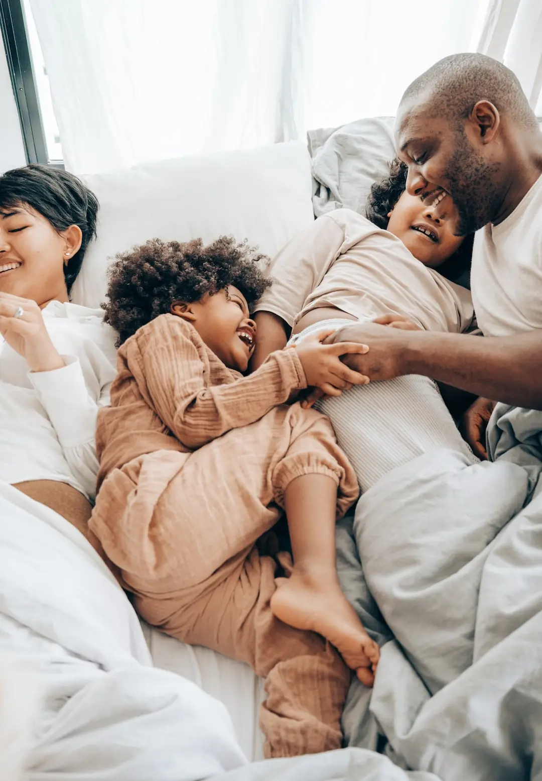 Family laughing together in a cool, comfortable bedroom